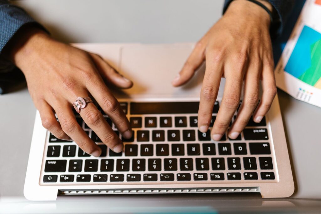 Hands typing on a laptop keyboard seen from above