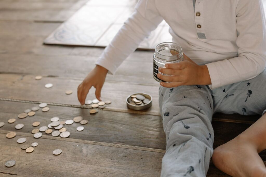 Child counting coins on a wooden floor